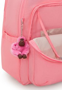 Rosa ryggsäck med stor dragkedjeficka som har en fluffig rosa gorillanyakel. Väskan har en slät tyggtextur och minimalistisk design.