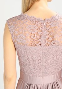 Robe en dentelle avec un haut en dentelle lavande clair à motifs floraux, un décolleté festonné et une jupe en satin lisse avec des plis.