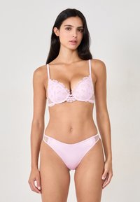 Set di lingerie rosa composto da un reggiseno con bordi in pizzo e decorazioni floreali, abbinato a perizoma coordinato, realizzati in un tessuto morbido e con un design con aperture.