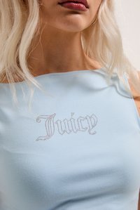 Ανοιχτό μπλε αμάνικο τοπ από μαλακό ύφασμα, με λογότυπο "Juicy" διακοσμημένο με ρουμπίνια στο μπροστινό μέρος. Λείος υφή.