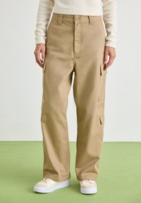 Khaki cargobroek met een rechte pijpdesign, voor sluiting met knoop en zijzakken. Gemaakt van duurzaam katoen. Gecombineerd met witte sneakers.