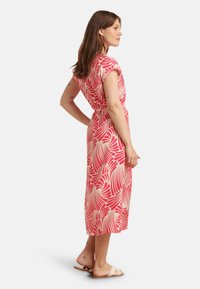 Blumenmuster Midi-Kleid in Rosa und Creme, mit kurzen Ärmeln, einer taillierten Taille und einer fließenden Silhouette. Kombiniert mit leichten Sandalen.