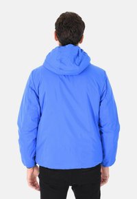 Giacca leggera di un blu brillante con cappuccio, caratterizzata da una vestibilità rilassata e polsini elasticizzati. Texture liscia e dettagli di cucitura minimi.
