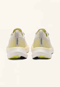 Beige és világossárga sportcipő pár hátrafele nézve, hálós anyaggal és saroknál húzófüllel ellátva.