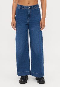 Wide-leg blue denim jeans with a high waist, featuring a front button closure and contrasting stitching. Smooth texture and clean hems.