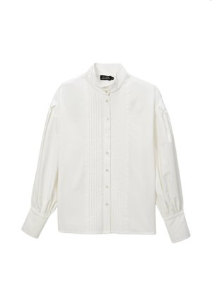 Blouse blanche avec un col haut, des manches longues et une fermeture à boutons. Présente des détails plissés sur le devant et des poignets froncés pour une texture.