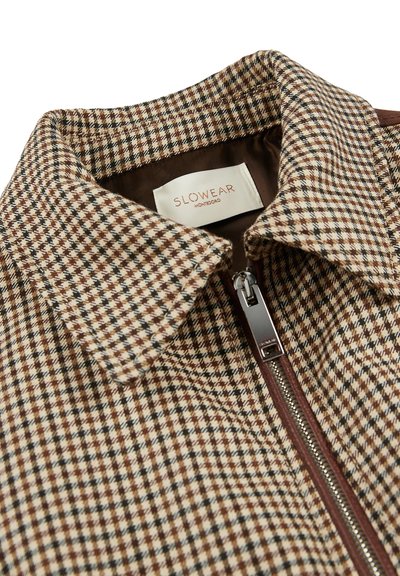 Giacca a motivo chevron marrone e crema con collo classico, chiusura con zip e fodera interna liscia. L'etichetta recita "SLOWEAR MONTEBORO."