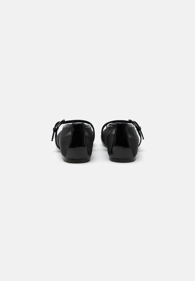 Paire de chaussures Mary Jane en cuir verni noir avec petits talons et brides à la cheville, vues de dos sur fond blanc.