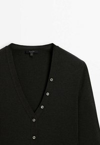 Cardigan nero a costine con scollo a V e cinque bottoni lucidi sul davanti. Tessuto morbido e design aderente.