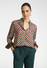 Camicia di seta con un motivo geometrico in bordeaux, blu e crema. Presenta un design con bottoni, maniche arrotolate e colletto.