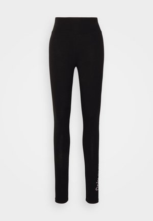 Juodos legging'os su aukštu juosmeniu, lygiu paviršiumi ir prigludusia forma. Apatinėje kojos dalyje yra subtilus gėlių raštas.
