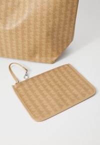 Torebka typu tote w kolorze opalizującym i dopasowana saszetka, obie z wytłoczonym geometrycznym wzorem. Saszetka posiada pasek na nadgarstek i metalowe okucia.