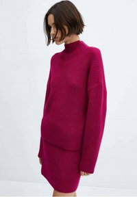 Fuksija pletena jopica z visokim ovratnikom in spušenimi rameni, v kombinaciji s skladno krilo do kolen iz istega materiala in barve.