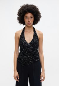 Top halter preto com lantejoulas, com um decote V profundo e design envolvente, apresentando uma textura suave e estilo sem mangas. Combinado com calças escuras.