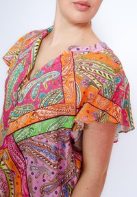 Bunte Bluse mit einem Paisleymuster und Rüschenschäften. Hergestellt aus leichtem Stoff in lebhaften Farbtönen von Pink, Orange, Grün und Blau.