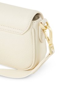 Světle béžová kožená crossbody taška s texturovaným povrchem, zlatými kovovými doplňky a odnímatelným popruhem. Obsahuje klopu na zapínání a zaoblený tvar.