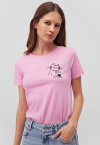 Light pink cotton t-shirt featuring a black cat graphic with a drink, round neckline, and short sleeves. Soft texture, casual fit.