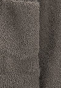 Nahaufnahme eines weichen, fuzzy grauen Stoffs mit plüschiger Textur, der feine Fasern und subtile Schattierungsvariationen zeigt.