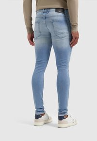 Ljusblå skinny jeans med en urtvättad yta, fem fickor och synlig sömnad. Kombineras med vita och marinblå sneakers.