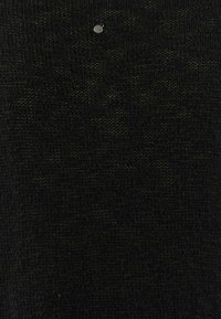 Svart stickad tyg med ett subtilt grönt mönster. Har en liten silverfärgad detalj på den övre delen.