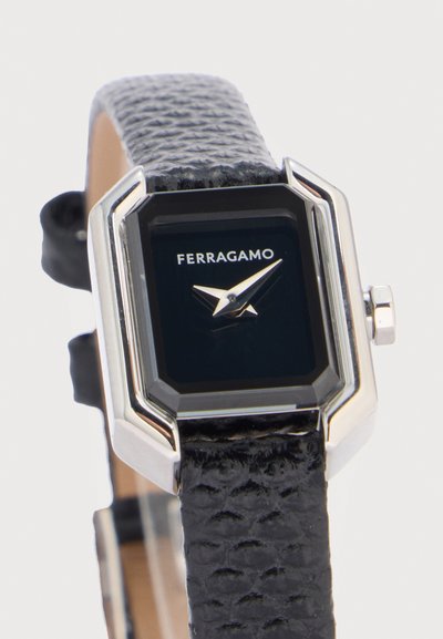 Montre-bracelet Ferragamo noire avec boîtier rectangulaire en argent et bracelet en cuir noir texturé, affichant les aiguilles des heures et des minutes sur le cadran.