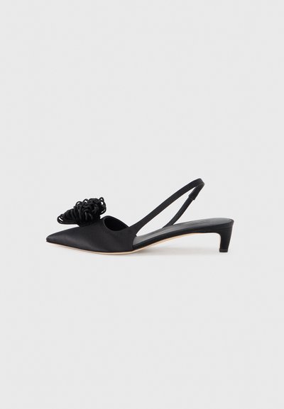 Chaussure à bride arrière en satin noir avec un bout pointu, ornée d'un accent floral texturé décoratif et d'un petit talon kitten bas.