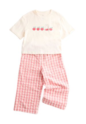 Cremeshirt mit kurzen Ärmeln mit roten Äpfeln und Hasengrafik, kombiniert mit rosa-weiß karierten, weitem Hosenbein.