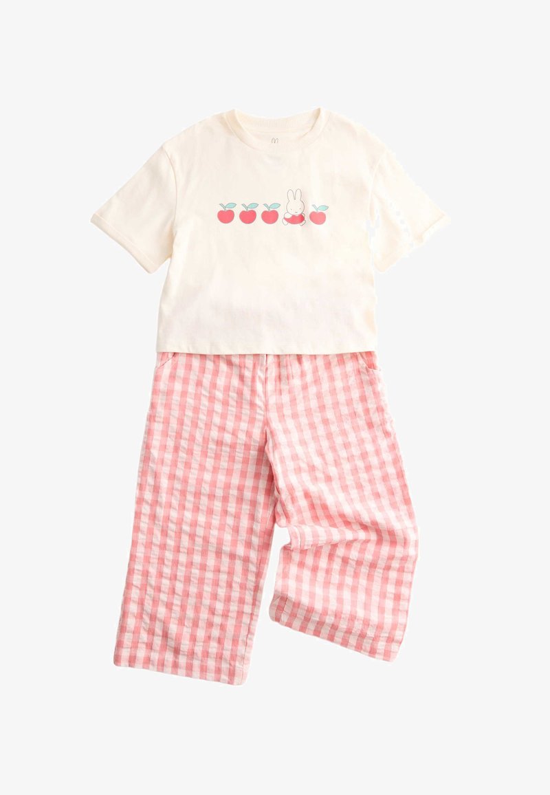 Camisa crema de manga corta con manzanas rojas y un gráfico de conejito combinada con pantalones anchos de cuadros rosados y blancos.