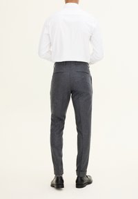 Szare wełniane spodnie o dopasowanym kroju, z gładką teksturą, z wykończonymi mankietami i dwoma tylnymi kieszeniami, zestawione z białą koszulą z długim rękawem.