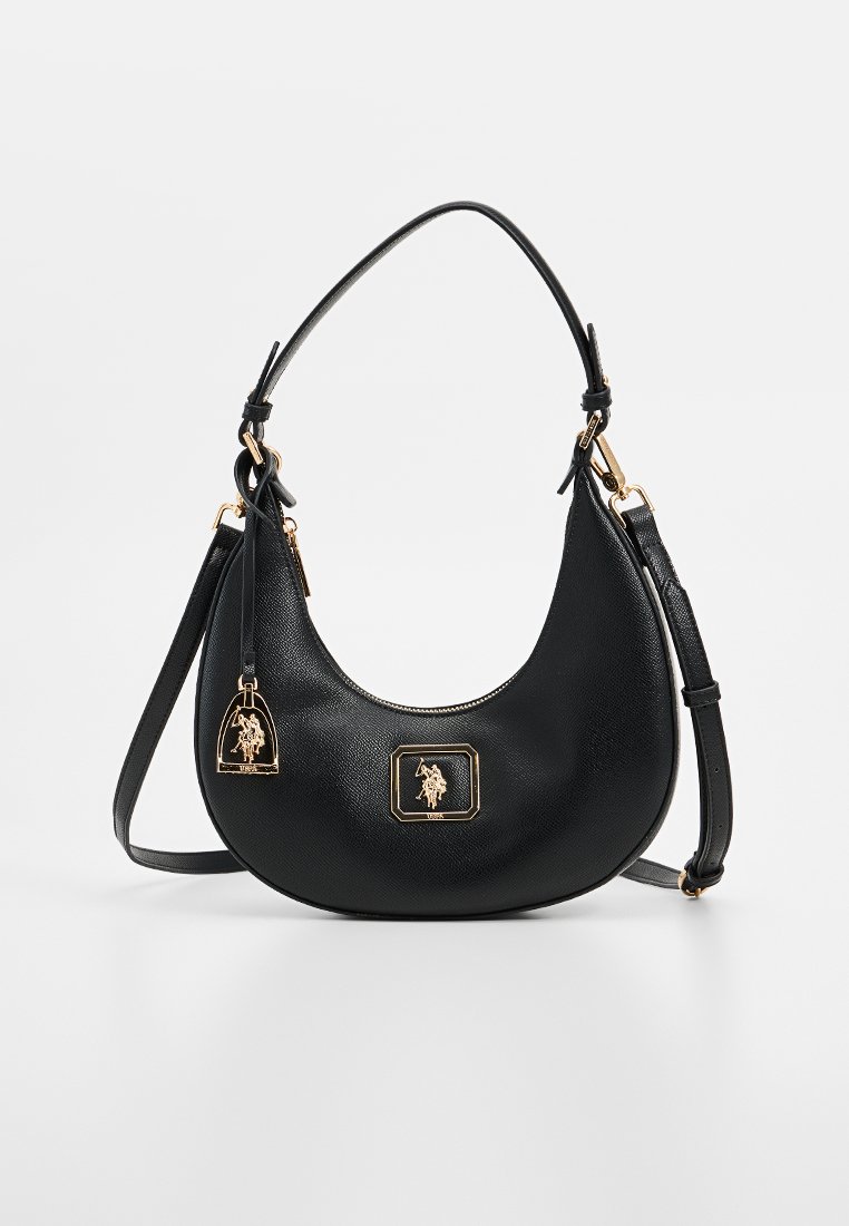 Sac à main en cuir noir avec une forme incurvée, des accessoires en métal doré et un logo embossé sur une étiquette carrée. Charm détachable inclus.