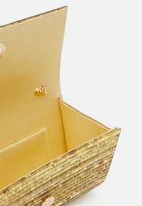 Borsa a tracolla intrecciata in giallo e marrone con un esterno a superficie liscia e un interno simile alla satinato, dotata di chiusura a scatto e slot per schede.