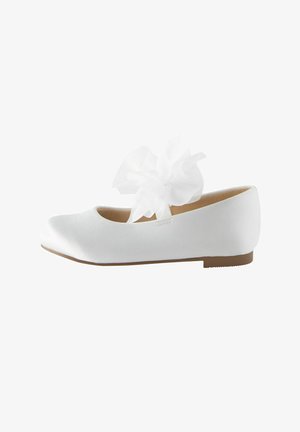 Chaussure plate blanche avec un bout rond et une grande décoration fleurie en tissu sur la bride du dessus.