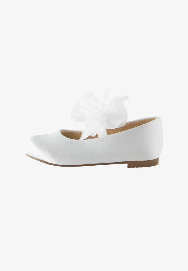 Chaussure plate blanche avec un bout rond et une grande décoration fleurie en tissu sur la bride du dessus.