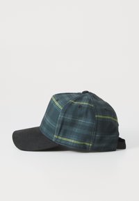 Casquette de baseball en tissu à carreaux vert foncé avec un bord noir. Dotée d'accents de couture jaunes et d'une sangle ajustable à l'arrière pour un ajustement parfait.