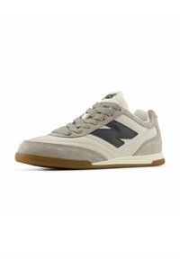 Niedrigschnittige Sneaker mit einem Obermaterial aus beigem Wildleder und Leder, einem dunkelgrauen Logo, einer Gummisohle und strukturierten Schnürsenkeln.
