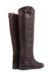 Bottes en cuir marron montantes avec une texture lisse. Dotées d'une fermeture éclair sur le côté et d'une sangle avec une boucle métallique en haut.
