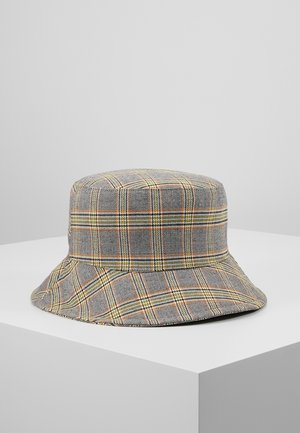 Gray bucket hat with orange, yellow, and black plaid pattern, displayed on a white pedestal against a gray background.