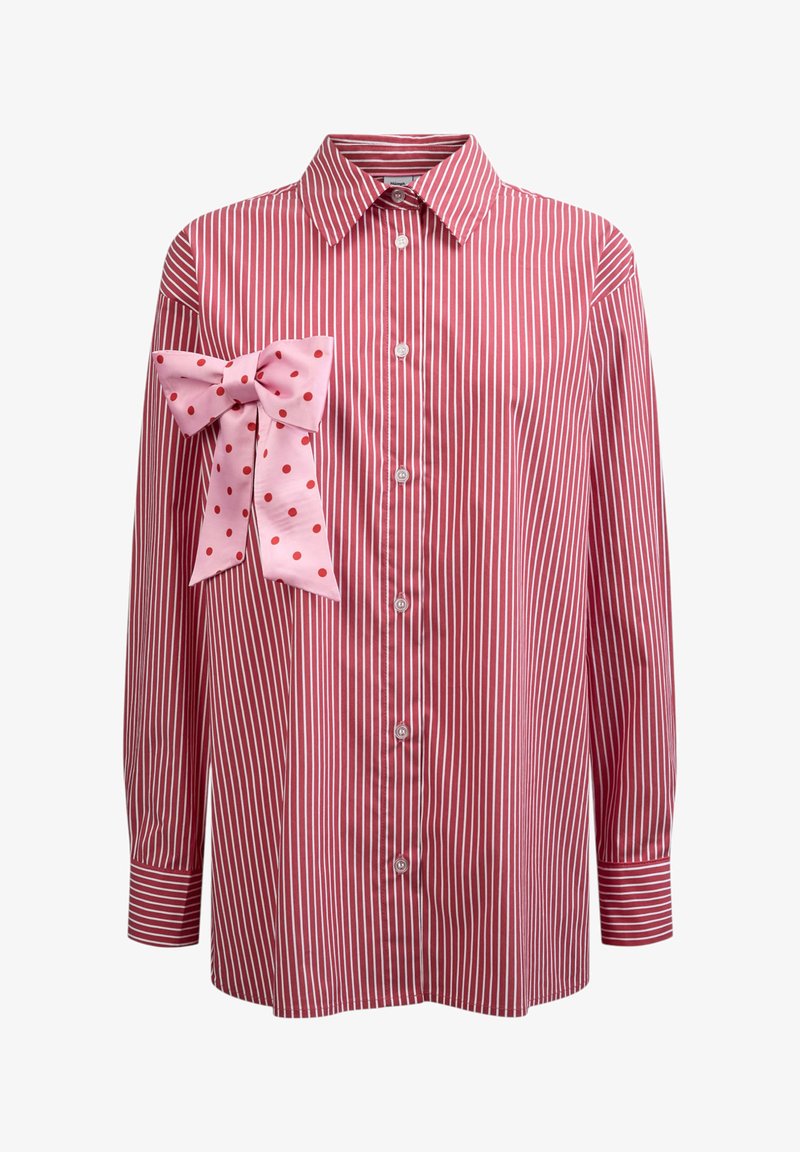 Chemise à manches longues rayée verticalement rouge et blanche avec col et boutons sur le devant, ornée d'un grand nœud rose à pois rouges sur la poitrine gauche.