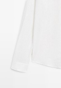 Manche de chemise blanche à manches longues avec de fines rayures verticales grises et un large poignet.