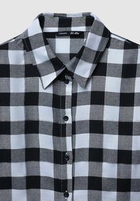 Camicia a quadri bianco e nero realizzata in tessuto morbido, con colletto a punta e chiusura a bottoni.