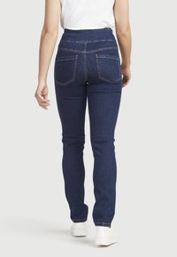 Tumman siniset korkeavyötäröiset farkut, joissa on ompeluakkentsseja, slim fit -leikkaus ja kaksi takataskua. Yhdistetty yksinkertaiseen valkoiseen t-paitaan ja valkoisiin tennareihin.