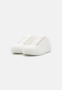 Baskets blanches avec dessus texturé présentant un motif circulaire, lacets plats et semelle en caoutchouc. Accent latéral près du talon. Design décontracté.