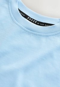 Hele sinine puuvillane T-särk ümara kaelusega. Omab sujuvat tekstuuri ja peenikest õmblust ning musta siltidega, millel on kiri "BAKER by TED BAKER".