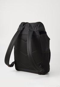 Black backpack with mesh back, adjustable straps, and a sleek design. Features a textured surface and subtle branding on the straps.