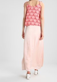 Rosa mönstrad linne med justerbara band parat med en flödande, ljusrosa maxikjol och vita klackskor.