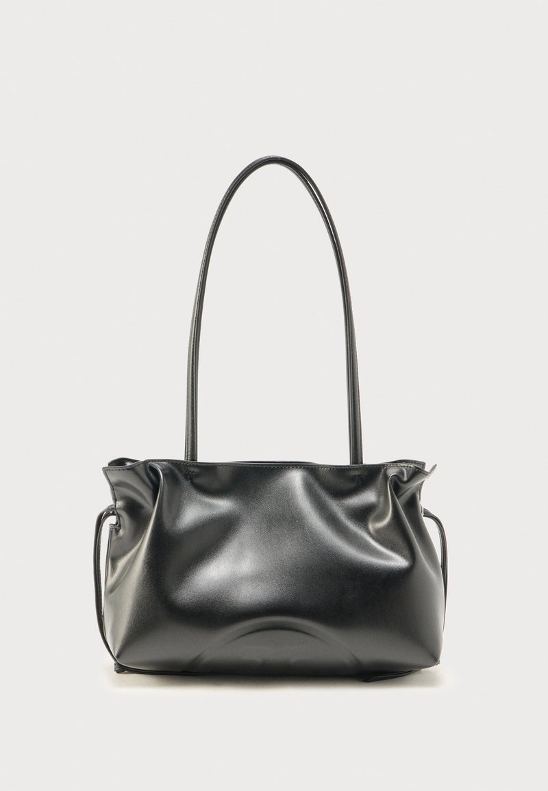 Μαύρη δερμάτινη τσάντα χειρός με ρυτιδωμένες λεπτομέρειες και ένα μακρύ, λεπτό λουράκι σε απλό ανοιχτό φόντο.