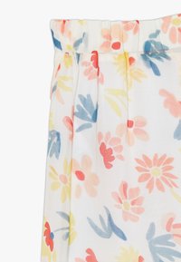 Tejido con estampado floral sobre una base blanca, con flores en tonos rosa, amarillo y azul. Cintura elástica y textura suave y ligera.