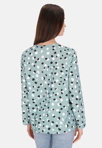Langzaamshirt met lange mouwen in mintgroen, met een all-over patroon van zwarte en witte stippen, ronde halslijn en een relaxte pasvorm.