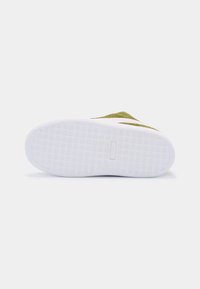 Baskets en daim vert avec une semelle en caoutchouc blanc texturé et un design minimaliste. Présente un talon plat et un branding simple sur la semelle.