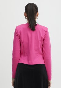 Figurvänlig långärmad jacka i starkt rosa tyg, med en slät textur och en något beskuren nederkant. Baksidan har sömdetaljer.